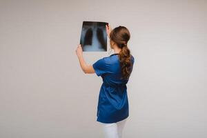 fêmea morena médico olhando às tomografia raio X filme foto
