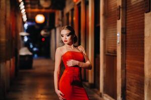 a elegante menina dentro uma vermelho tarde vestir em a ruas do a noite cidade do marselha.a mulher dentro uma vermelho tarde vestir dentro França foto