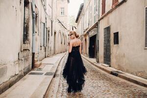 uma à moda noiva dentro uma Preto Casamento vestir poses dentro a antigo francês cidade do Avinhão. modelo dentro uma lindo Preto vestir. foto tiro dentro provence.