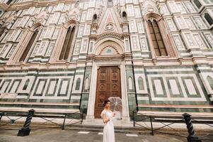 uma lindo à moda noiva com a guarda-chuva anda em através a velho cidade do florença.modelo com guarda-chuvas dentro Itália.Toscana. foto