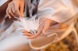 brincos com branco franja dentro a mãos do a noiva às uma Casamento dentro Itália.casamento brincos branco peludo dentro Toscana foto