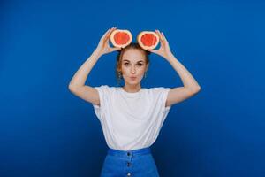 surpreso, a rindo menina detém a Toranja gostar ouvidos. vegano estilo de vida. sorridente mulher , comendo conceito.dieta orgânico , peso perda e saudável Comida. batidos e fresco suco. foto