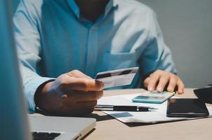 mãos de homens estão segurando um cartão de crédito. pagamentos de negócios online e compras online foto