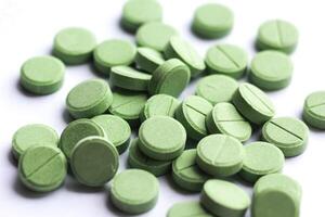 amontoar do espalhados hortelã verde cor médico pílulas comprimidos em branco fundo foto