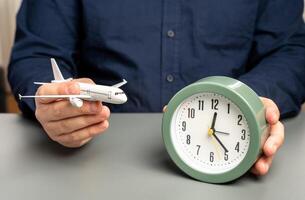 uma homem detém uma passageiro avião e uma relógio. voar tempo. planejamento uma rota com transferências. foto