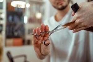 fechar-se do cabeleireiro mãos segurando tesouras e corte cliente cabelo foto