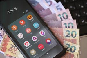 Kyiv, Ucrânia - fevereiro 28, 2024 namoro apps ícones em Smartphone exibição e brasileiro reais dinheiro foto