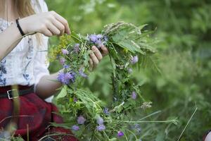 guirlanda para a feriado kupala. mãos tecer uma guirlanda do selvagem flores e ervas. foto