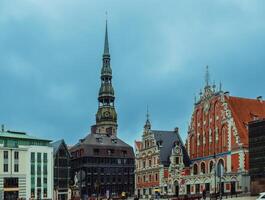 cidade corredor quadrado com casa do a cravos pretos e santo Peter Igreja dentro velho Cidade do riga em dramático nascer do sol, letônia1 foto