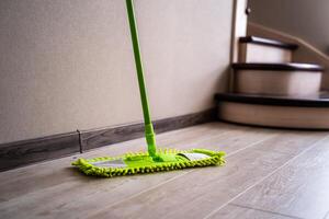 verde esfregão em pé perto branco muro. limpeza engrenagem. doméstico. foto