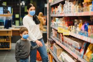 mãe e filho estão compras às a mercearia loja. elas vestem máscaras durante quarentena. coronavírus pandemia .coved-19 clarão. a epidemia do a vírus. foto