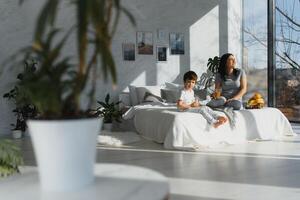 mãe com filho dentro pijamas comendo fruta em cama. retrato feliz, sorridente, alegre família, mãe e filho tendo café da manhã dentro cama, surpresa em mãe dia. positivo humano emoções foto