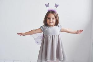 acredito que posso voar. adorável garotinha com fantasia de fada em pé na sala com fundo branco foto