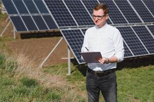 solar painéis e azul céu.homem em pé perto solar painéis. solar painel produz verde, ambientalmente amigáveis energia a partir de a Sol. foto