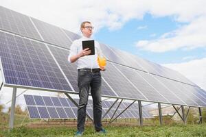 solar painéis e azul céu.homem em pé perto solar painéis. solar painel produz verde, ambientalmente amigáveis energia a partir de a Sol. foto