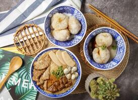 sortido Macarrão sopa com claro, abalone, mee sua, almôndegas, ostra, carne, ampla intestino, compreensivo Macarrão com pauzinhos e colher servido dentro tigela isolado em mesa topo Visão do chinês Comida foto