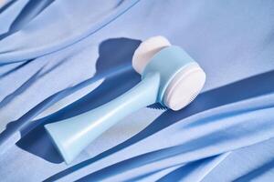 azul massageador de escova para a face em uma fundo do azul seda. foto