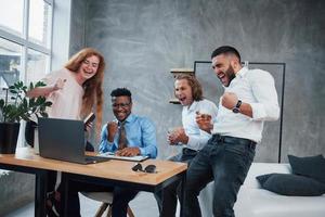 as pessoas se alegram com a vitória. grupo de funcionários multirraciais em roupas formais conversando sobre tarefas e planos foto