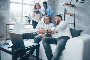 cara mostrando resultados. grupo de funcionários multirraciais em roupas formais conversando sobre tarefas e planos foto