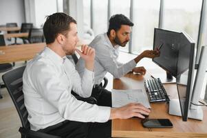 dois homens comerciantes sentado às escrivaninha às escritório juntos monitoramento ações dados vela gráficos em tela analisando preço fluxo sorridente alegre tendo lucro trabalho em equipe conceito foto