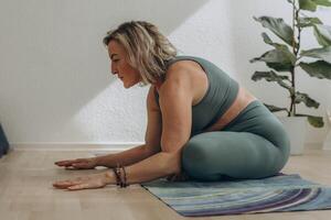 uma 50 anos mulher faz ioga às casa foto
