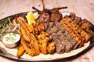 sortido misturar grelha com frango tikka, carne kabab, Carneiro Churrasquinho, asas boti, malai, cortar, shish tawook servido dentro prato isolado em fundo topo Visão do árabe Comida foto