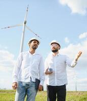 dois engenheiros discutindo contra turbinas em vento turbina Fazenda. foto