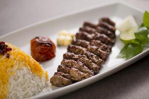 quelo Kebab com Biryani arroz e salada servido dentro prato isolado em cinzento fundo topo Visão do árabe Comida foto