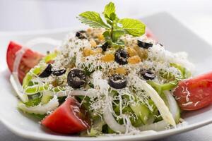 salada e Tabrizi com Oliva, tomate, pepino cebola e hortelã servido dentro prato isolado em cinzento fundo topo Visão do árabe Comida foto