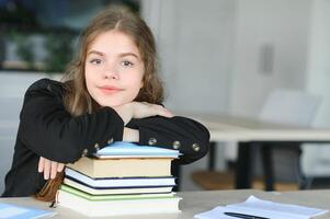 uma fofa 15 anos de idade estudante senta às uma escola escrivaninha com cadernos e livros e estudos foto