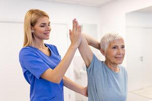 médico ou fisioterapeuta trabalhando examinando tratando ferido braço do Senior fêmea paciente, alongamento e exercício, fazendo a reabilitação terapia dor dentro clínica. foto