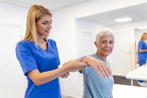 cuidador ajudando contente Senior mulher exercício às clínica. reabilitação para mais velho, Senior médico Cuidado. mais velho mulher retornando para Boa Estado do saúde foto