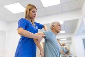 médico ou fisioterapeuta trabalhando examinando tratando ferido braço do Senior paciente, alongamento e exercício, fazendo a reabilitação terapia dor dentro clínica. foto