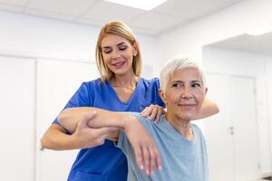 médico ou fisioterapeuta trabalhando examinando tratando ferido braço do Senior fêmea paciente, alongamento e exercício, fazendo a reabilitação terapia dor dentro clínica. foto