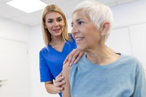 mulher médico osteopata dentro médico uniforme fixação Senior mulher pacientes ombro e costas juntas dentro manual terapia clínica durante Visita. profissional osteopata durante trabalhos com paciente conceito foto