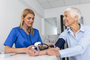 medindo sangue pressão. Senior mulher ter uma Visita com fêmea médico dentro moderno clínica. medindo sangue pressão. pressão medidor. hipertensão e Alto coração taxa foto