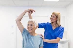 fisioterapeuta mulher dando exercício com haltere tratamento sobre braço e ombro do Senior fêmea paciente fisica terapia conceito foto