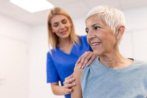 mulher médico osteopata dentro médico uniforme fixação Senior mulher pacientes ombro e costas juntas dentro manual terapia clínica durante Visita. profissional osteopata durante trabalhos com paciente conceito foto