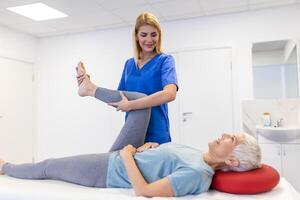 fisioterapeuta trabalhando com paciente dentro clínica, fechar-se. uma moderno reabilitação fisioterapia trabalhador com Senior cliente, fisica terapeuta alongamento paciente joelho foto