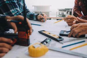 engenheiro pessoas encontro trabalhando e apontando às uma desenhos dentro escritório para discutindo. Engenharia Ferramentas e construção conceito. foto