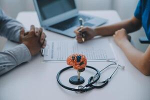 médico explicando cérebro funções para paciente em modelo dentro escritório. foto