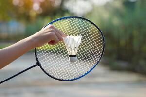 uma pessoa segurando uma peteca na frente de uma raquete de badminton, conceito para badminton ao ar livre jogando nos tempos livres, foco suave e seletivo. foto