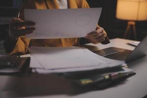 mulher de negócios usando a calculadora para fazer finanças matemáticas na mesa de madeira no escritório e no plano de trabalho de negócios, impostos, contabilidade, estatísticas e conceito de pesquisa analítica foto