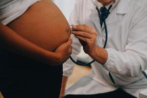 fêmea médico é verificação grávida mulher com estetoscópio. conceito carinhoso para grávida mulher foto