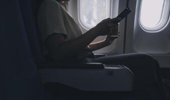 ásia mulher desfrutando goza uma café confortável voar enquanto sentado dentro a avião cabine, passageiros perto a janela. foto