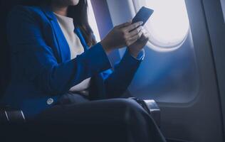 usando Móvel e computador portátil, pensativo ásia pessoas fêmea pessoa a bordo, avião janela, perfeitamente capturar a antecipação e excitação do feriado viagem. chinês, japonês pessoas. foto