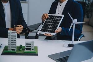 dois jovem engenheiros perícia dentro solar célula instalação Encontros e discussão dentro a trabalho. planejamento para instalar solar fotovoltaico painéis em cobertura topo dentro a escritório quarto com fábrica construção plano. foto