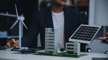 dois jovem engenheiros perícia dentro solar célula instalação Encontros e discussão dentro a trabalho. planejamento para instalar solar fotovoltaico painéis em cobertura topo dentro a escritório quarto com fábrica construção plano. foto