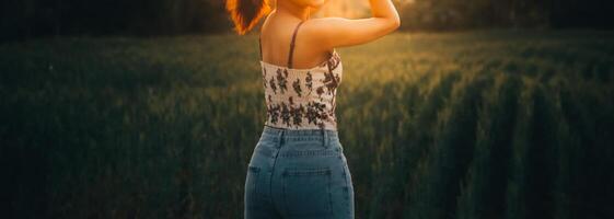 jovem bonita mulher dentro vermelho verão vestir e Palha chapéu caminhando em amarelo Fazenda campo com maduro dourado trigo desfrutando caloroso tarde. foto