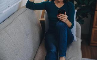 empresário de felicidade bela jovem asiática de negócios usar celular de uso casual para compras on-line desfrutar com mídia social e laptop em casa startup de pequenas empresas online banking foto